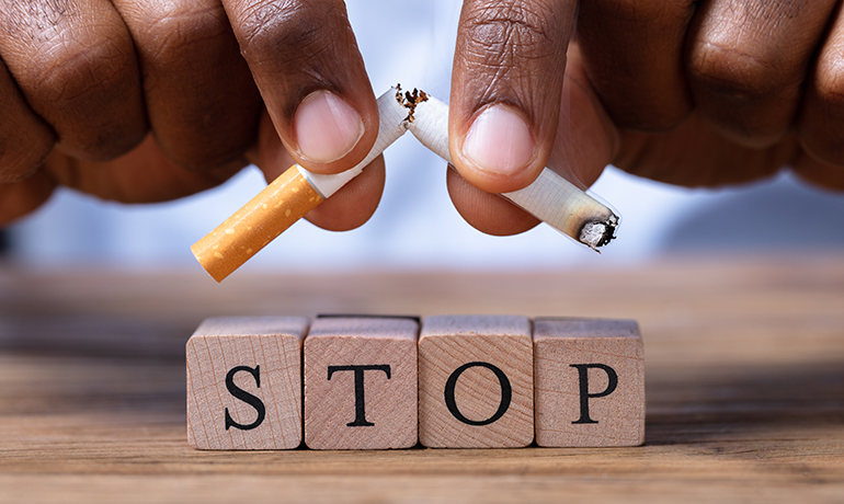 Close-up Of A Man's Hand Breaking Cigarette Over Wooden Stop Blocks.
