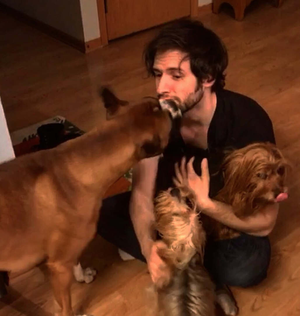 Daniel Principe sitting on the floor with his three dogs.